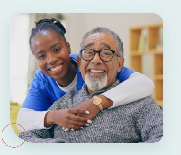 A smiling Blue Haven caregiver in blue scrubs hugging an older man at home in Northern Virginia